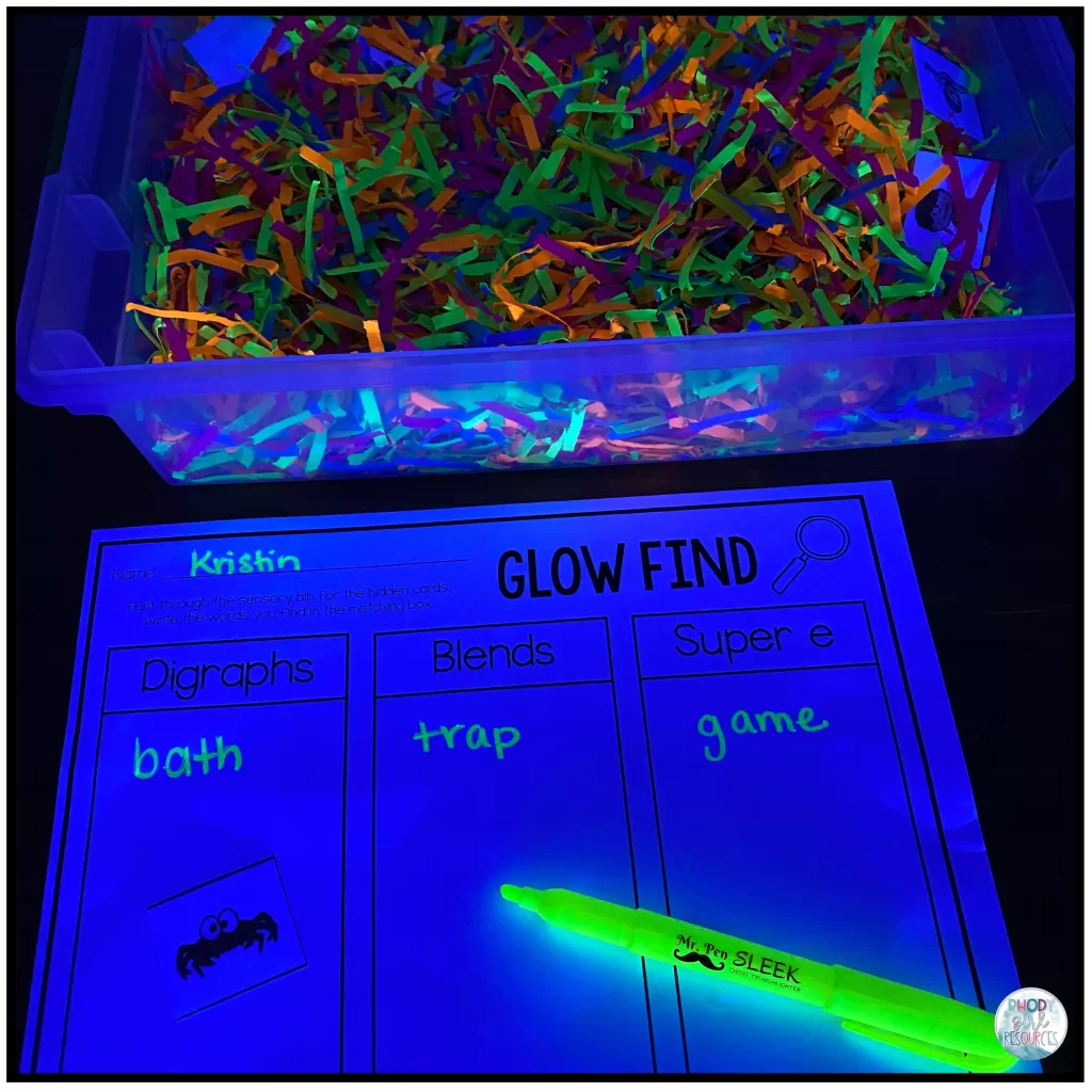 A  sensory bin filled with shredded paper and picture cards to play "Glow Find."